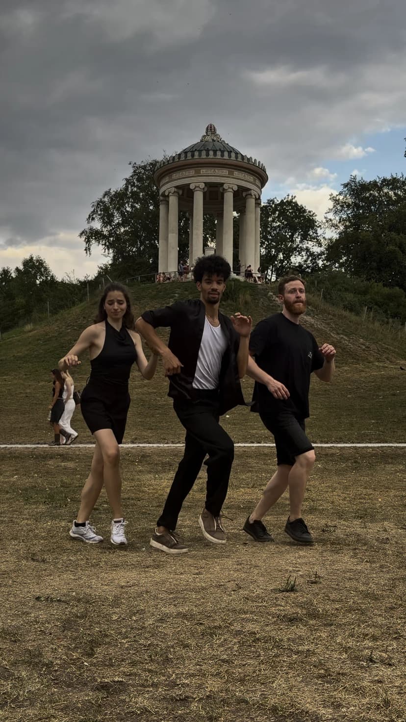 Three dancers mid-step in a Munich park